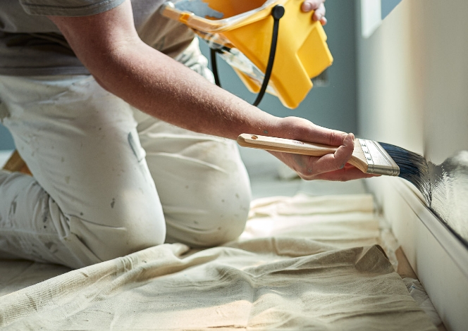 Professional painter cutting in around wall edges with a brush.