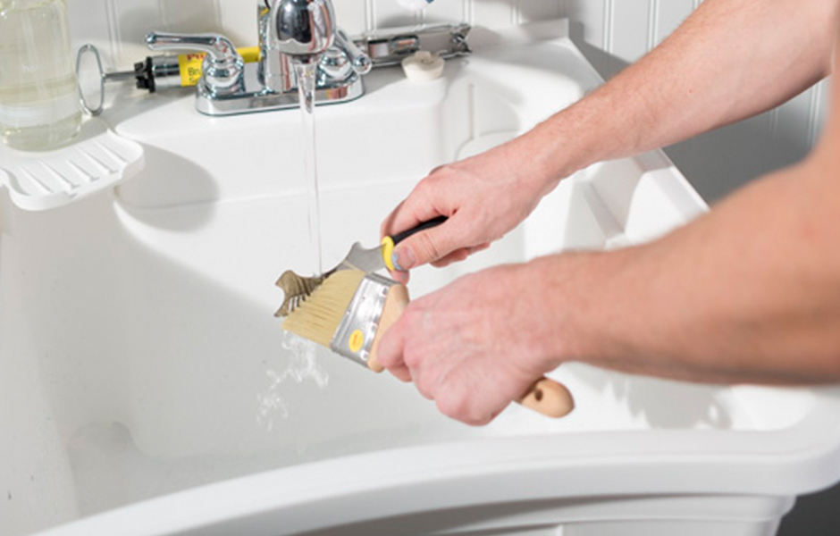 Painter cleaning a brush in a sink