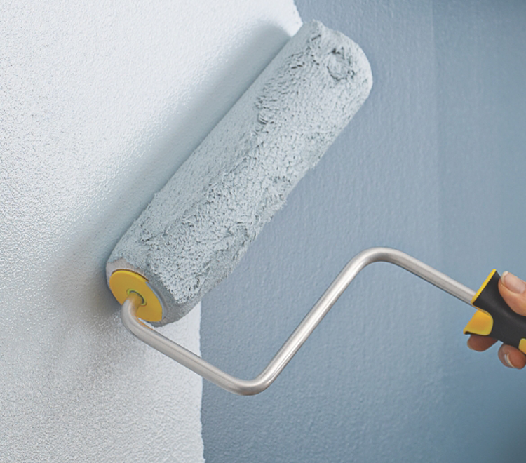 Painter applying light gray paint on kitchen wall with a Purdy roller creating a smooth finish