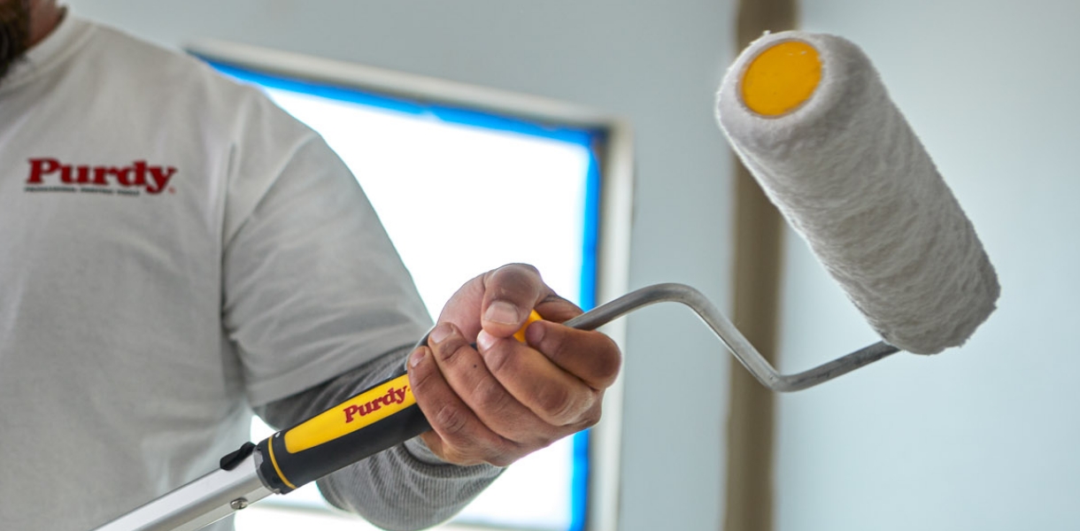 Pro painter attaching a nine-inch roller frame to an extension pole.