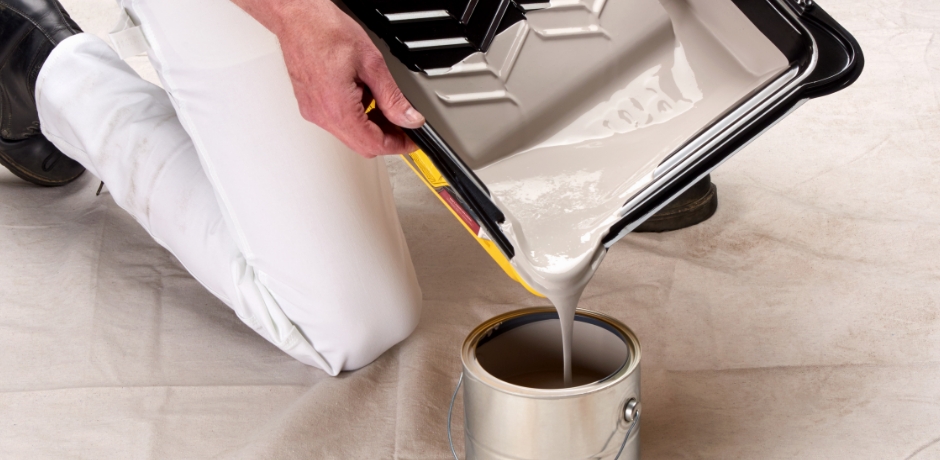 Pro painter at a jobsite pouring paint back into a can using a tray and liner pour spout