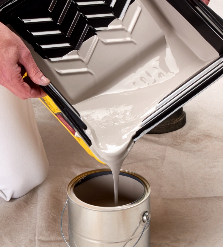 Pro painter at a jobsite pouring paint back into a can using a tray and liner pour spout