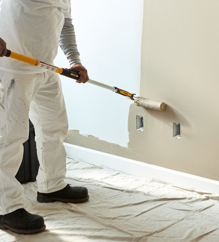 Professional painter painting an interior wall using a beige color.