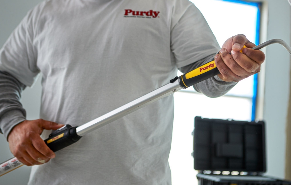 Pintor profesional que conecta el armazón de un rodillo a la vara de extensión.