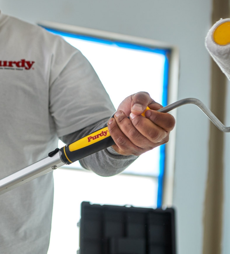 Pintor profesional que conecta el armazón de un rodillo a la vara de extensión.