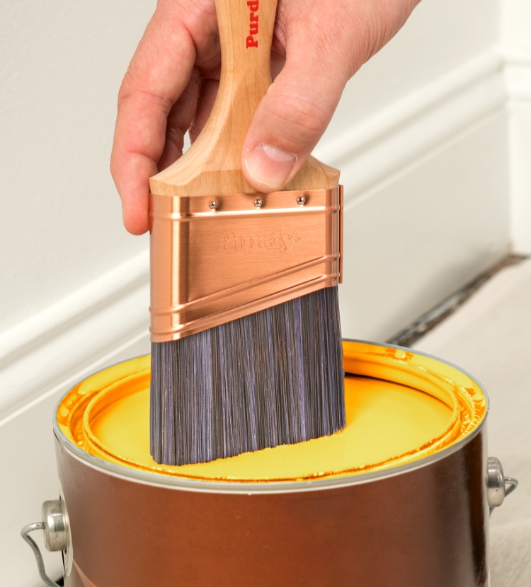 Sumergir una brocha Purdy en una lata de pintura.