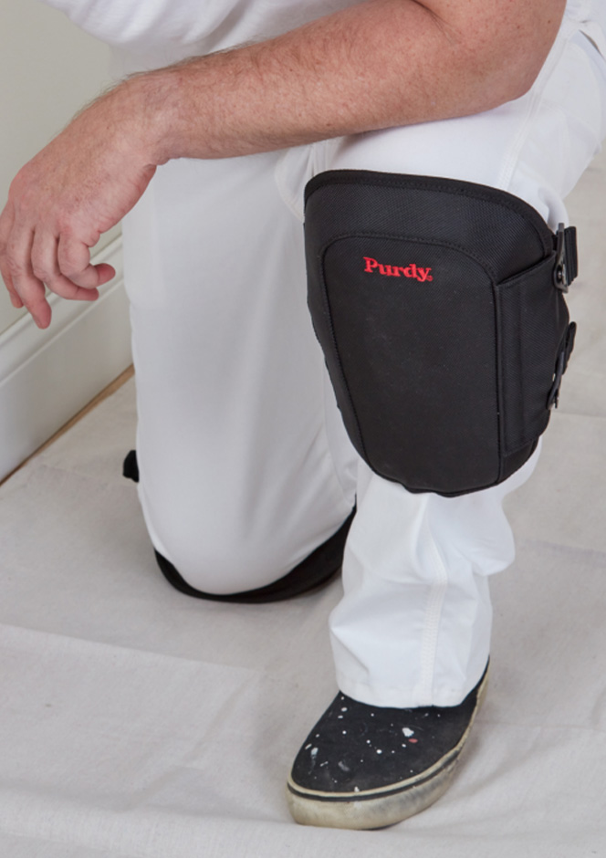 guy kneeling with Purdy knee pads while painting a wall