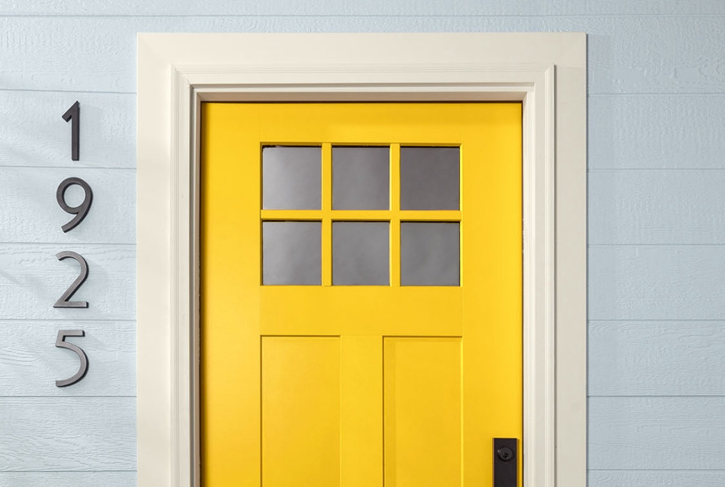 Modern front door painted bright yellow color with white trim.