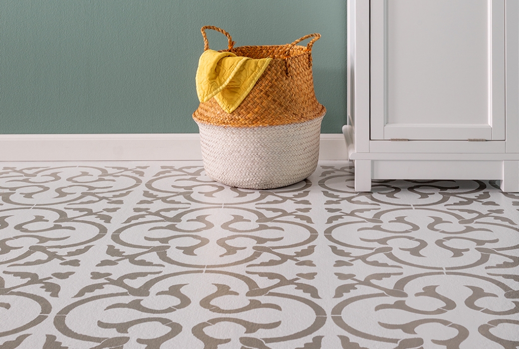 Detail of the finished stenciled floor with a white cabinet and a straw basket.