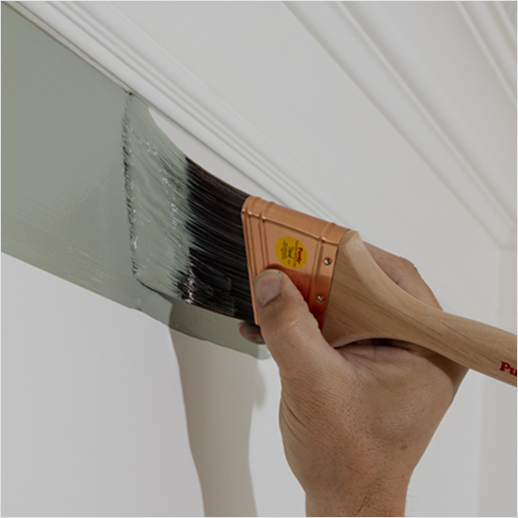 Using a Purdy brush to cut in on a wall below crown molding.