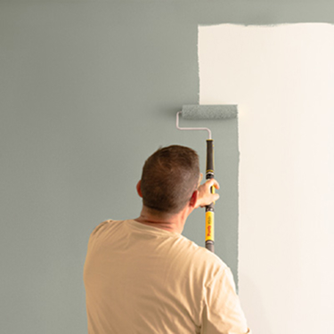 Professional Painter rolling paint on a wall with a Purdy roller and pole.