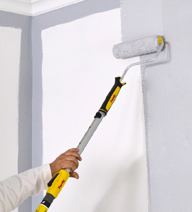 Professional Painter rolling paint on a wall with a Purdy roller, cover and pole.
