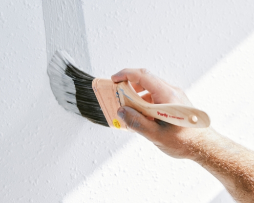 Pro painting a wall with a Purdy brush.