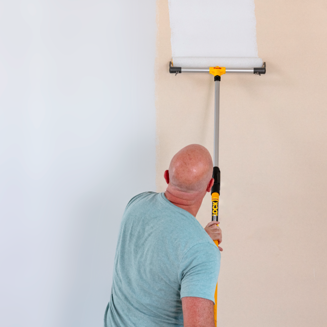 Pro painter covering a large wall with an eighteen-inch roller.
