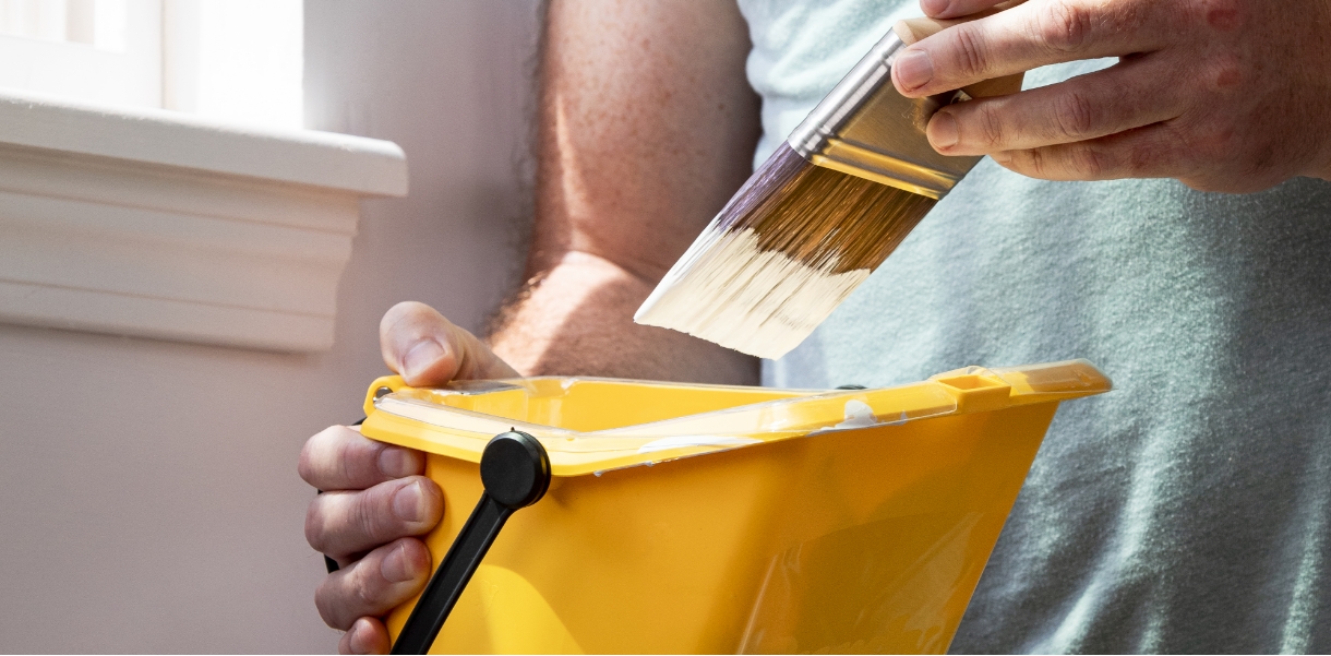 Pro painter holding a brush and Purdy Pail near a window