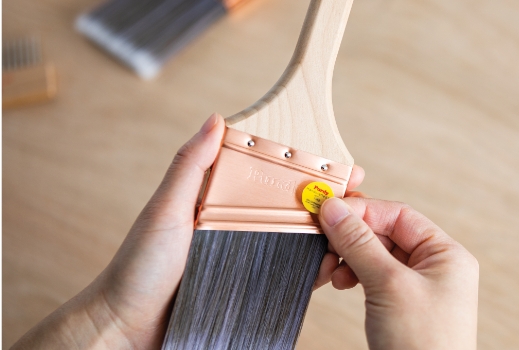 Brushmaker applying signature yellow sticker to a brush.