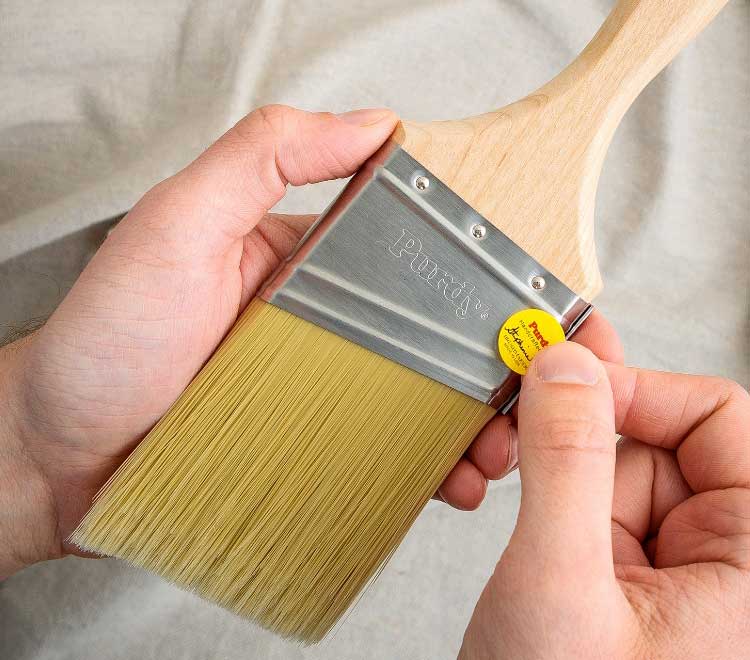 Brushmaker applying a yellow sticker with their signature to a new brush.