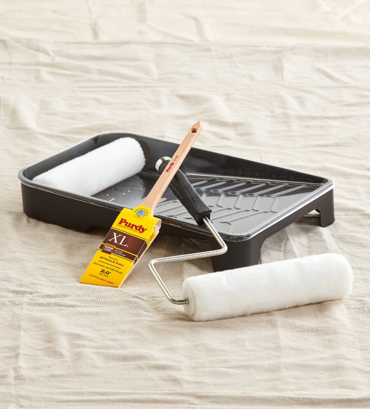 Purdy brush, roller and a paint tray on drop cloth.