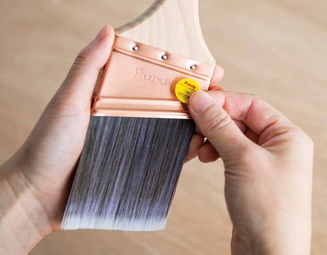 Brushmaker placing a signed sticker on a new paintbrush.