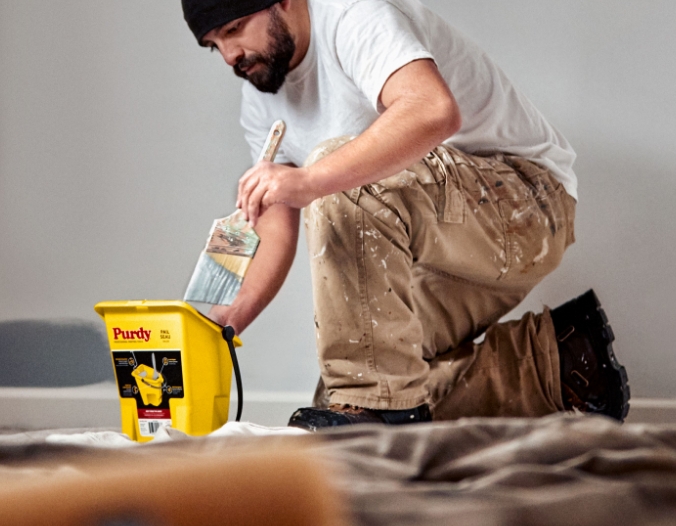 Pro painter dipping a paint brush into a Purdy Pail.