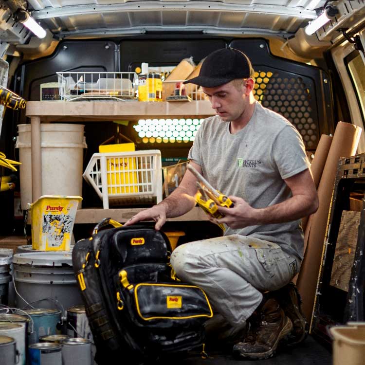 Young professional painter organizing brushes in his work truck.