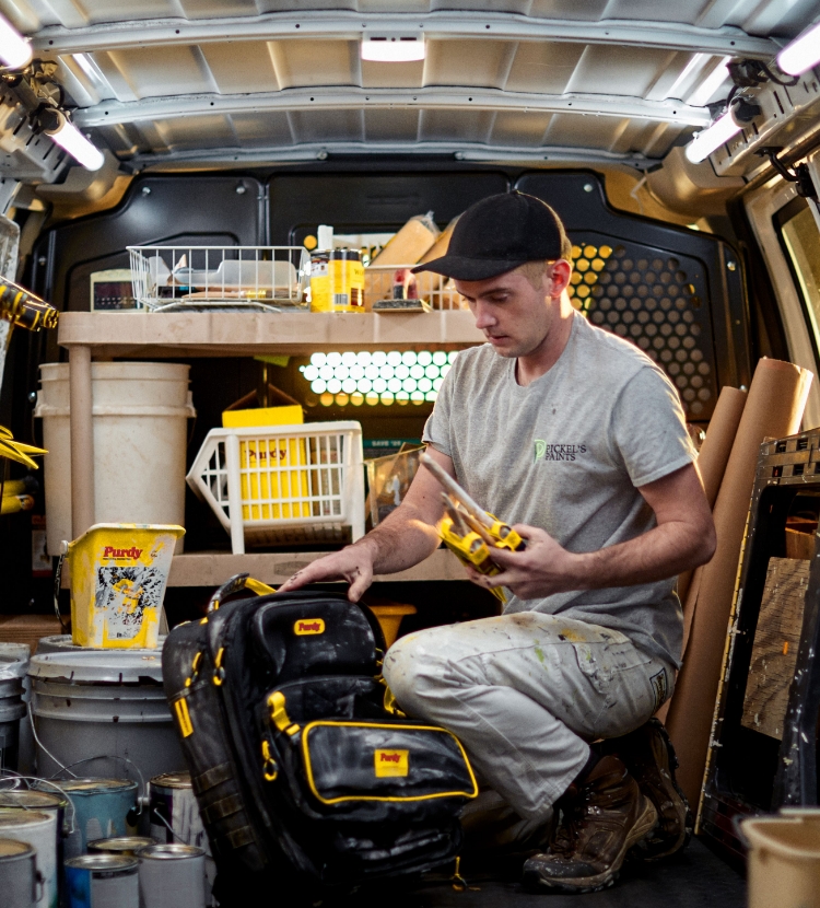 Young professional painter organizing brushes in his work truck.
